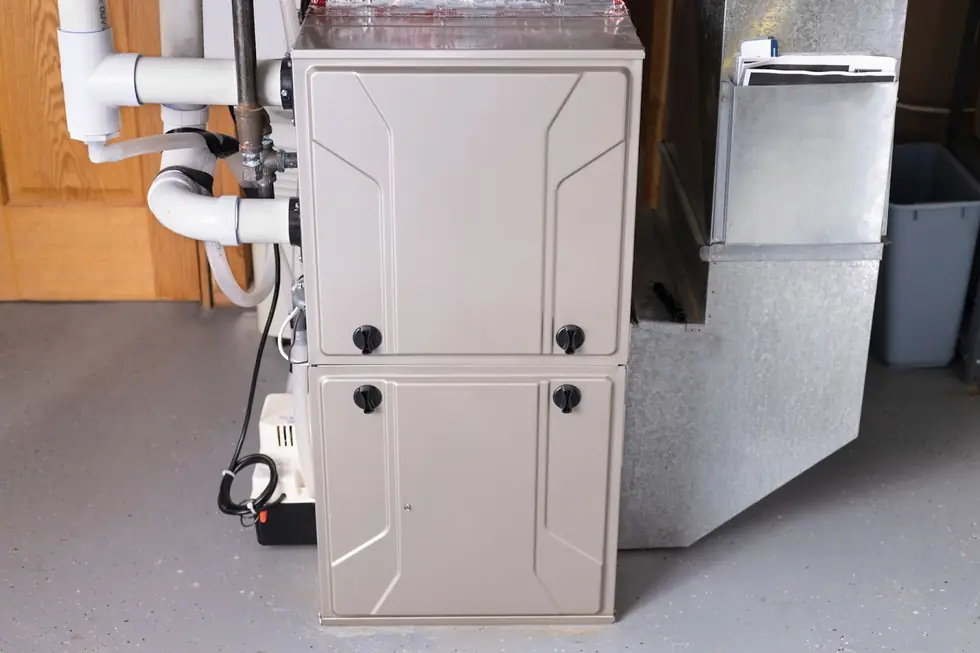 Gas furnace with white PVC venting installed in a garage