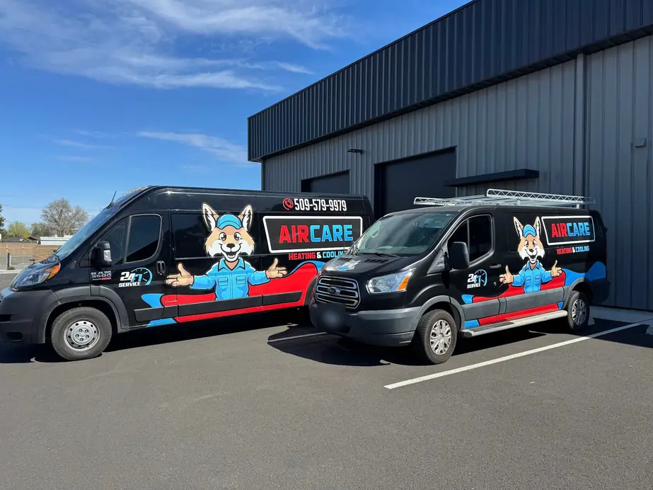 Both AirCare service vans, the Ram and the Ford, parked outside a metal shop building