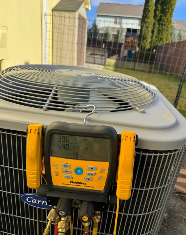 Fieldpiece manifold gauges hung on a Carrier condenser during a diagnosis