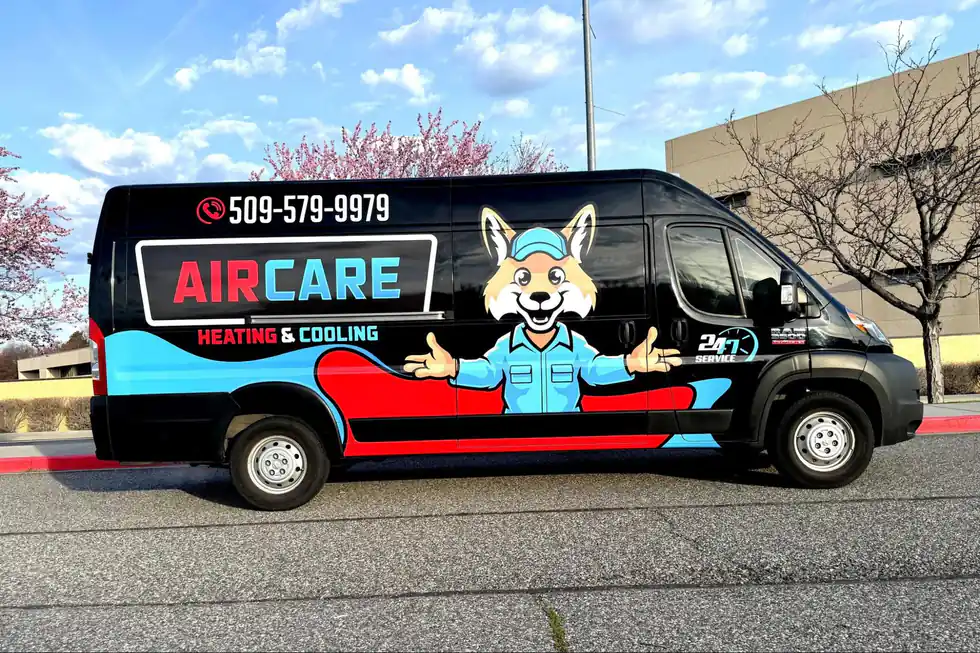 AirCare's black service van with the fox mascot and phone number on the side, parked in front of blossoming trees